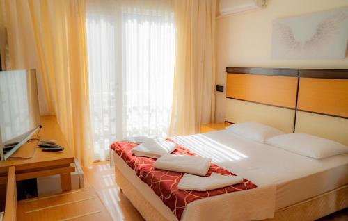 1 dormitorio con 1 cama, TV y ventana en Platanus Hotel Altınoluk, en Altinoluk