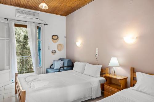 a bedroom with two beds and a chair and a window at Oceanis Rooms in Mikros Gialos