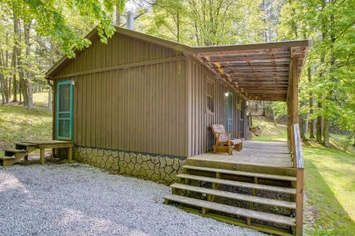 a small cabin with a wooden porch and a bench at Cozy Green Bank Cabin about 2 Mi to Observatory! in Dunmore