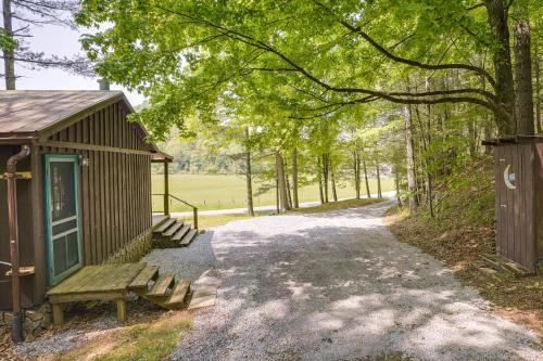 a small building with a bench next to a road at Cozy Green Bank Cabin about 2 Mi to Observatory! in Dunmore