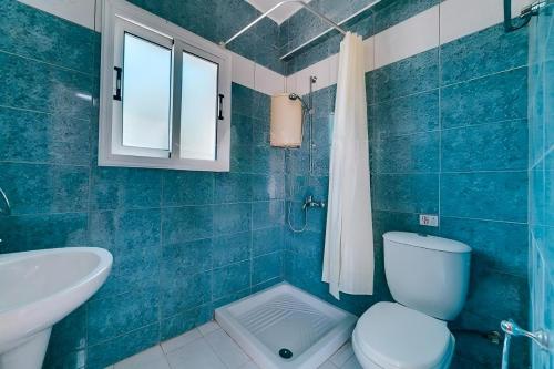 bagno piastrellato blu con servizi igienici e lavandino di Summer Breeze - Cheerful 2 bedroom villa with pool a Ayia Napa