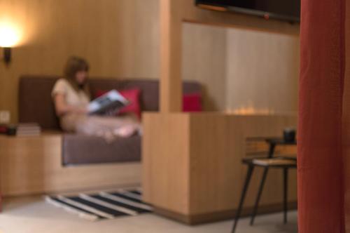 a woman sitting on a couch reading a book at MiHotel Sala in Lyon