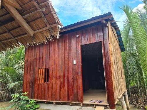 een klein houten gebouw met een zwarte deur bij Nam Binh Homestay in Ben Tre