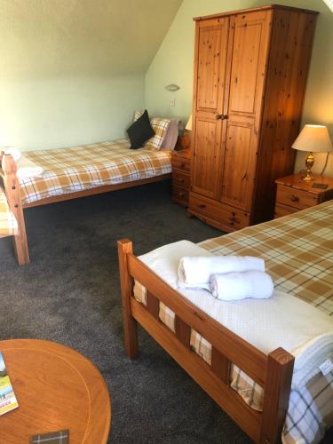 a bedroom with two beds and a wooden cabinet at Elgin Guest House in Elgin