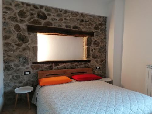 una camera con un letto e un muro in pietra di Deiana a Santu Lussurgiu