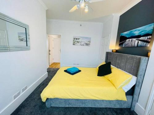 a bedroom with a large yellow bed with a blue pillow at NEW modernised flat in the heart of Leigh on Sea in Southend-on-Sea