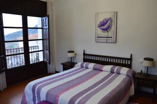a bed room with a bed, chair and a window at Hostal de Montaña la Casa Grande in Nogueruelas
