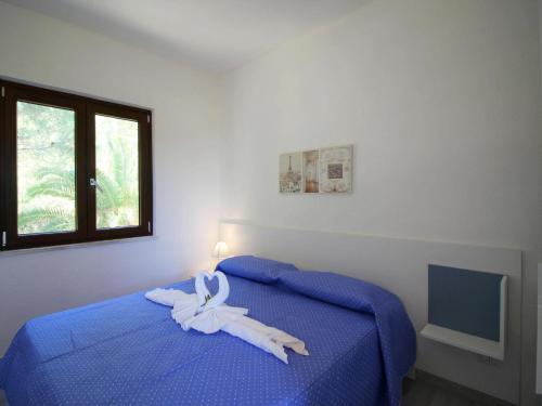 Un dormitorio con una cama azul con toallas blancas. en Apartment in Costa Rei en Monte Nai