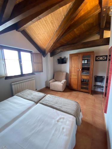 a bedroom with a large white bed and a chair at Hotel rural Monasterio de Ara Mada in Santa Colomba de las Arrimadas