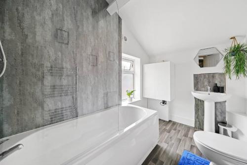 een badkamer met een wit bad en een wastafel bij Fabulous and Stylish House in Nottingham in Mansfield