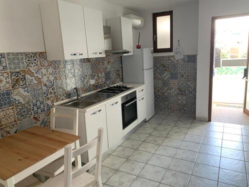 a kitchen with white cabinets and a wooden table and a sink at Residence R&B Tyrrhenum in Monte di Procida