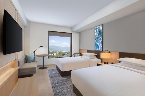 a hotel room with two beds and a large window at Fairfield by Marriott Dehradun in Dehradun
