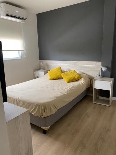 1 dormitorio con 1 cama con 2 almohadas amarillas en Departamento Alvear en Paraná