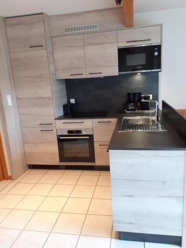 a kitchen with wooden cabinets and a black counter top at Les Adrets in Gérardmer
