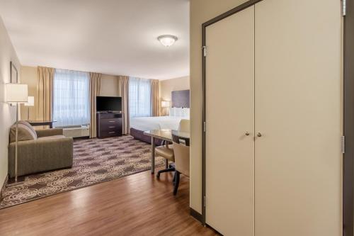 ein Hotelzimmer mit einem Kingsize-Bett und einem Tisch in der Unterkunft Landmark Suites - Williston in Williston