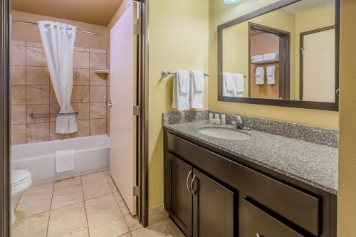 a bathroom with a sink and a tub and a toilet at Landmark Suites - Williston in Williston
