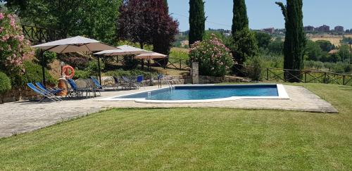 a swimming pool in a yard with chairs and umbrellas at Case in campagna con piscina a Todi in Todi