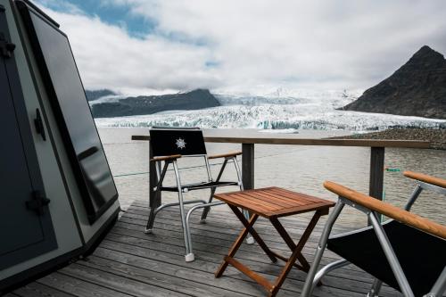 einen Tisch und Stühle auf einer Terrasse mit Blick auf einen Gletscher in der Unterkunft Fjallsarlon - Overnight adventure in Hof