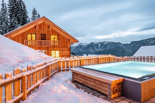 a log cabin in the snow with a swimming pool at Poolchalet Dachsteinblick in Pruggern