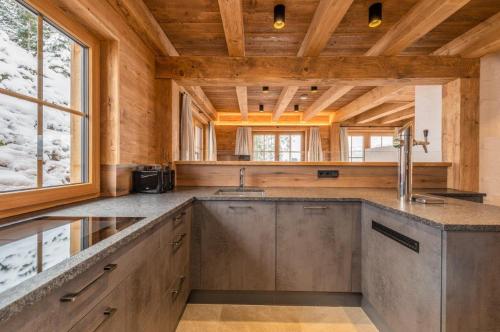 a kitchen with wooden ceilings and a large counter top at Poolchalet Dachsteinblick in Pruggern