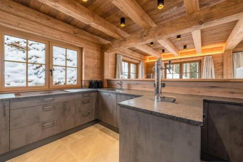 a large kitchen with wooden walls and wooden ceilings at Poolchalet Dachsteinblick in Pruggern