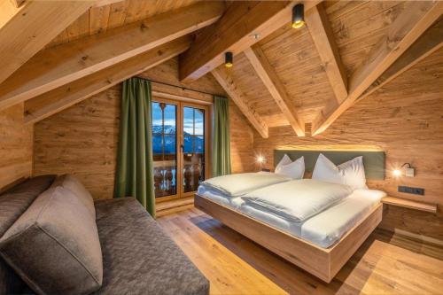 a bedroom in a log cabin with a bed and a couch at Poolchalet Dachsteinblick in Pruggern