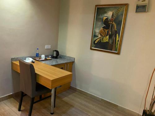 a desk with a painting of a man with a gun on the wall at La Cour Hotels and Apartments Cooper in Lagos