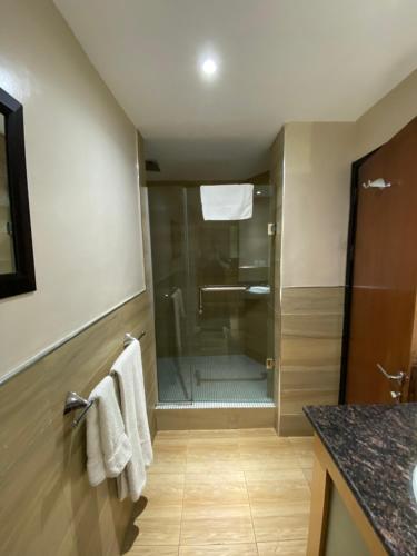a bathroom with a shower and towels on a wall at La Cour Hotels and Apartments Cooper in Lagos