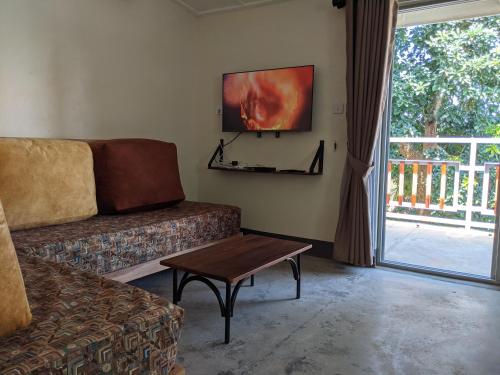 ein Wohnzimmer mit einem Sofa, einem Tisch und einem Fenster in der Unterkunft Dutchess Hotel and Restaurant in Fort Portal