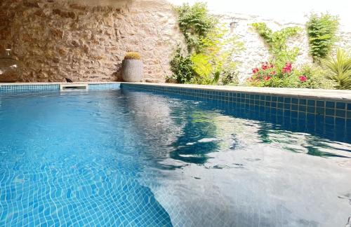 una piscina azul con una pared de piedra en L'Oiseau Bleu ROLLIER, en Roubia