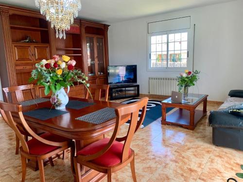 a living room with a dining room table with flowers on it at Villa Felicidad in Vilanova i la Geltrú