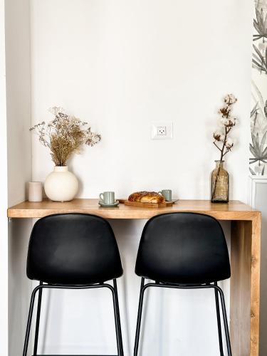 a wooden table with two black chairs in a room at בקתות שחר in Yonatan