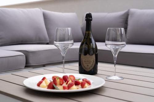 una mesa con una bandeja de fruta y dos copas de vino en BLUETTE SUITE & BOAT, en Polignano a Mare