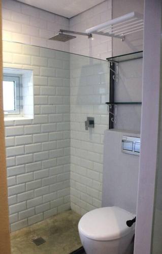 a white bathroom with a toilet and a window at Well Appointed Apartment by ARPA Hospitalities in Stellenbosch