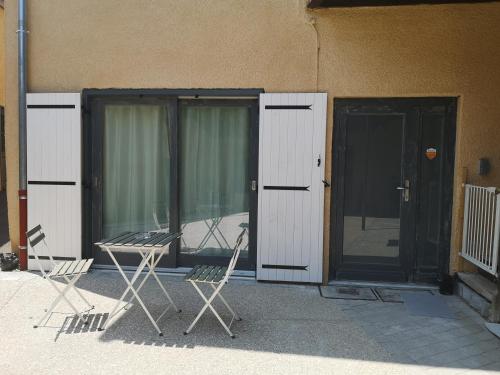 two chairs and a table in front of a building at Proche Hôpital LyonSud Metro B Calme et WiFi in Pierre-Bénite