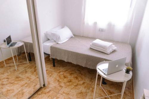 a small room with a bed with a laptop on it at Villa Felicidad in Vilanova i la Geltrú