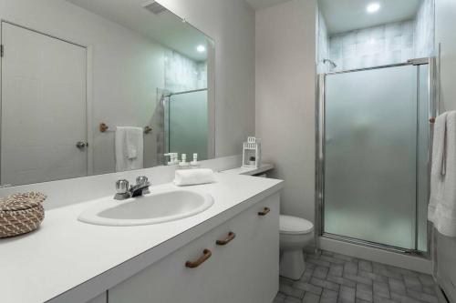 a white bathroom with a sink and a shower at Tremblant Mountain Resort Condo! in Mont-Tremblant