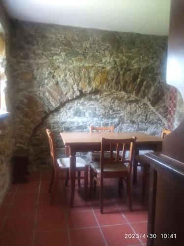 una sala da pranzo con tavolo, sedie e parete in pietra di Popetto casa vacanza a Tresana