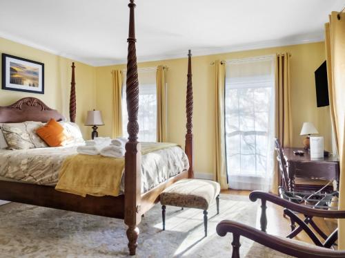 a bedroom with a bed and a chair and a desk at The Thistle Inn in Boothbay Harbor