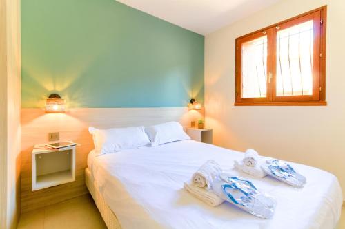 een slaapkamer met een groot wit bed en handdoeken bij SELECT'soHOME - Charmant T2 proche de la plage de Saint-Clair au Lavandou avec parking privé - PARCFO11 in Le Lavandou