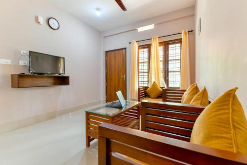 a living room with two benches and a tv at OYO Home Elegant Stay Fine Nest Homes in Kalpetta