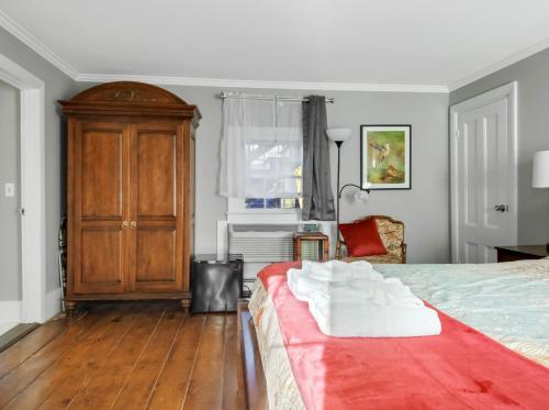 a bedroom with a bed and a wooden cabinet at The Thistle Inn in Boothbay Harbor