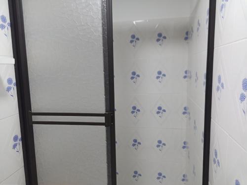 a glass shower door with blue flowers on the wall at Glamping IKIGAI in Marinilla