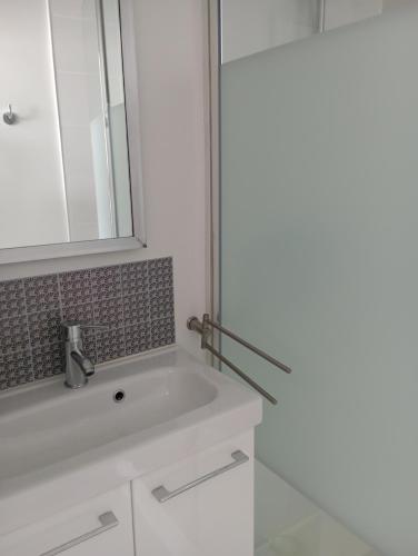 een badkamer met een witte wastafel en een spiegel bij Le Pornizhan in Pornichet