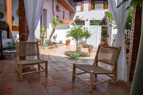 two chairs sitting on a patio with white curtains at Amelia Apts & Rooms in Alghero