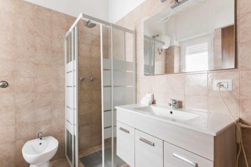 een badkamer met een wastafel, een toilet en een spiegel bij Seamoon Home Nettuno in Nettuno