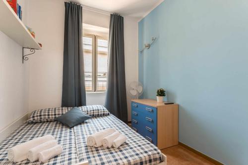 a small bedroom with a bed and a blue wall at Home Romana Centro Nettuno in Nettuno