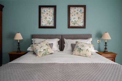 a bedroom with a bed with pillows and two windows at The School House in Ashburton