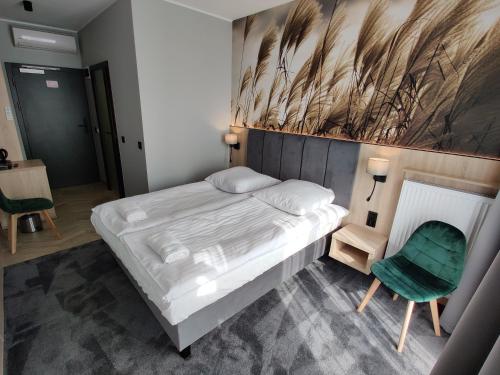 a bedroom with a large bed and a green chair at Nowe M4 Żyrardów Centrum - blisko Suntago in Żyrardów