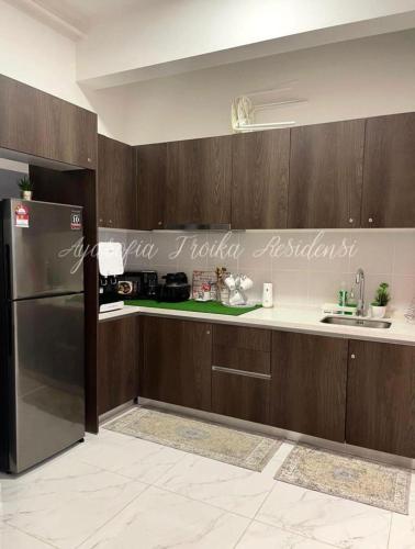 a kitchen with wooden cabinets and a stainless steel refrigerator at AYASOFIA TROIKA CITY VIEW ( Wifi, Netflix, 4-6 pax) in Kota Bharu